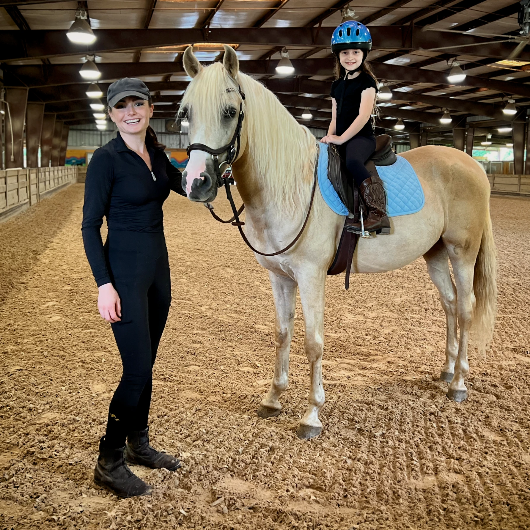 Madison Lareau beside a palomino pony with a young rider in the saddle at Little Creek Horse Farm